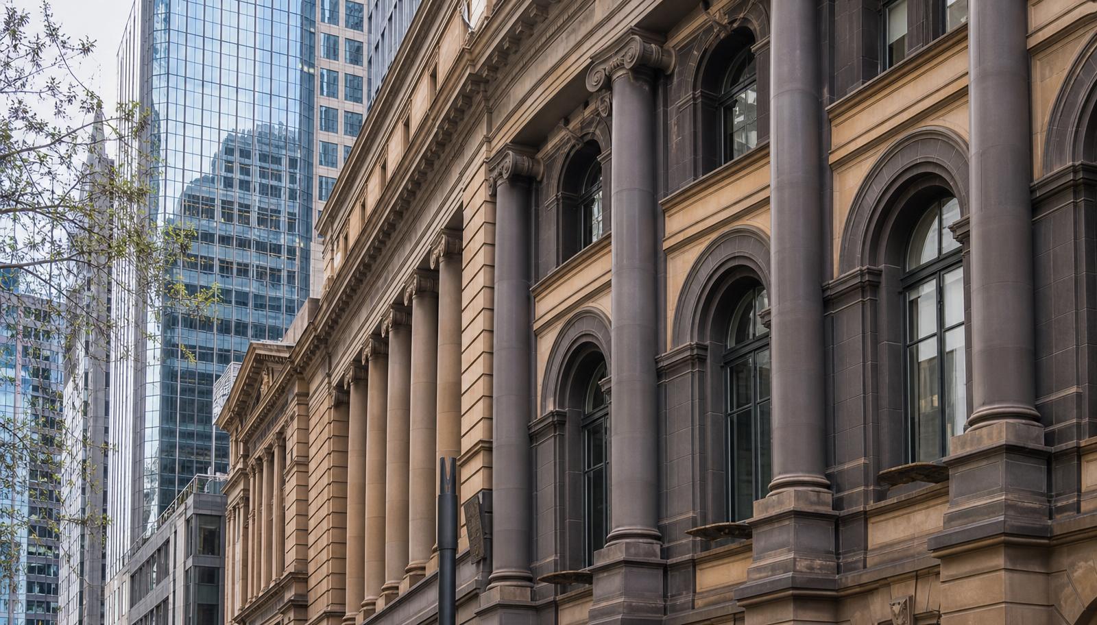 Classical stone banking facade beside a modern office tower in Melbourne's financial district